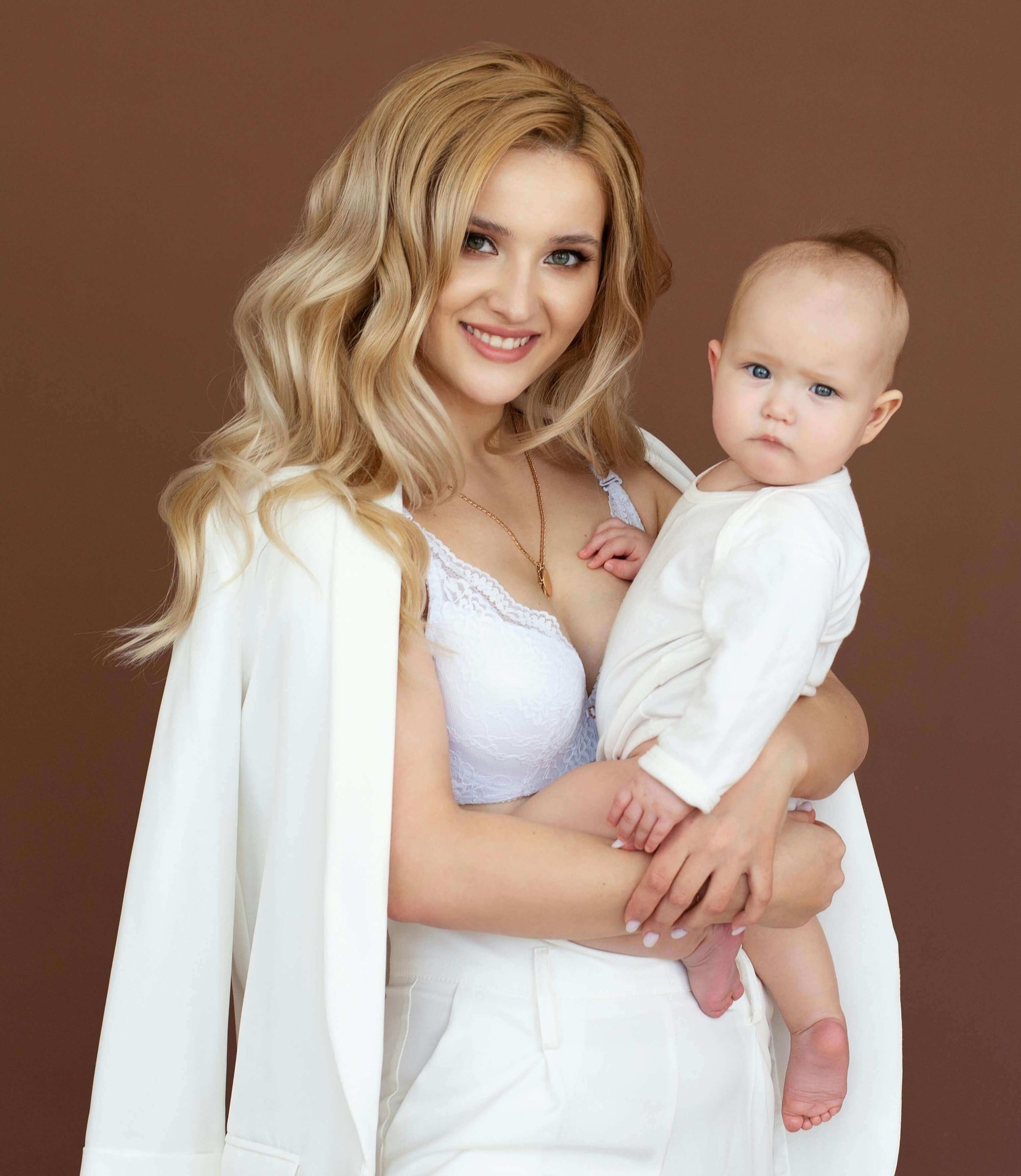 Mom holding a baby in a professional outfit, representing wearable pumps for office moms.
